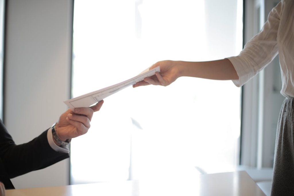 Cropped photo of a person handing over documents to the other